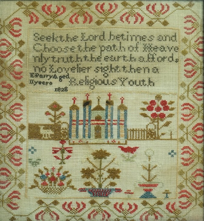 A framed 1828 cross stitch sampler dated 1828 by E Parry aged 11years. Embroidered in reds, greens and blues with religious verse and a central motif of a building, tree, flowers and sheep, above panel of spot motifs of